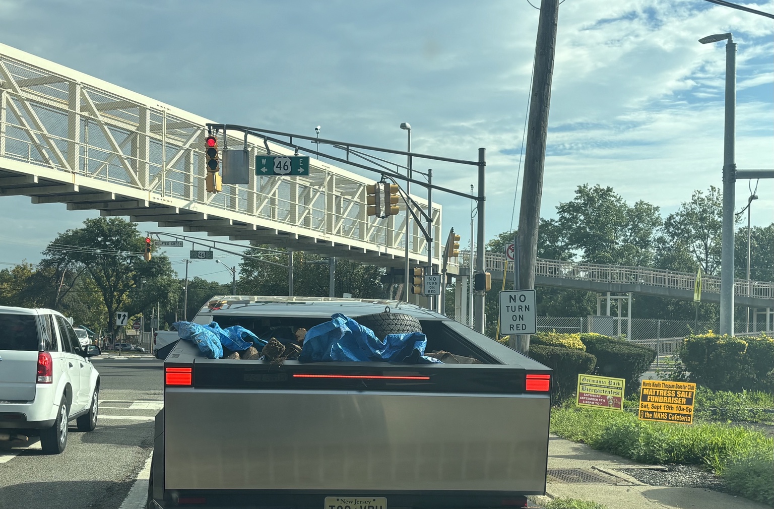 Cybertruck carrying logs, blue tarps and a plastic crate at Franklin and Route 46